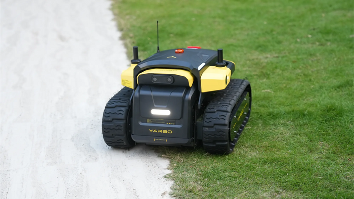 Yarbo Core robot on a lawn next to a gravel path