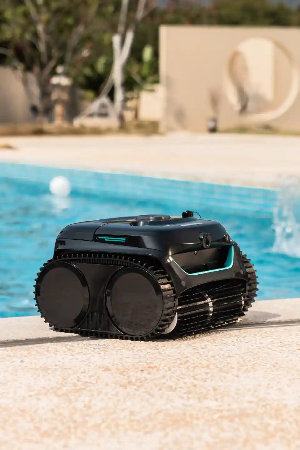 WYBOT cordless robotic pool cleaner at the edge of a backyard pool